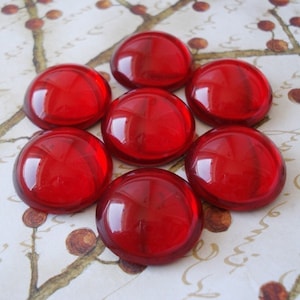 May include: Eight round, red glass cabochons. The cabochons are smooth and shiny.
