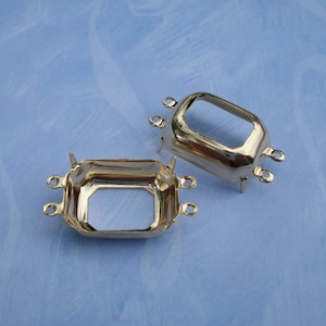 May include: Two silver-toned metal settings for bezel settings. Each setting has four prongs and a square opening.