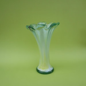 May include: A white ceramic mug with a black handle and the text "But First, Coffee" in a black, bold font. The mug is on a white surface.