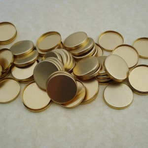 May include: A pile of round, gold-colored metal discs. The discs are smooth and have a shiny finish.