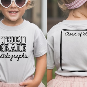 May include: A light gray t-shirt with black text that reads "THIRD GRADE autographs" and a graphic of a pen. The back of the shirt has a black outlined rectangle with the text "Class of '26".