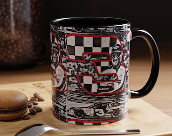 May include: A black coffee mug with a black handle and interior. The mug features a racing theme with the number 3 in red, a checkered flag design, and a portrait of a race car driver.