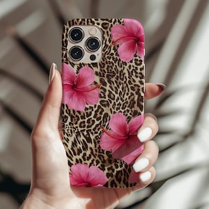 May include: A phone case featuring a leopard print background and pink hibiscus flowers. The case has a camera lens cutout and a black border.