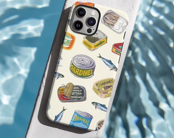 以下が含まれることがあります： 缶詰のイワシと魚の模様が描かれた白いiPhoneケース。ケースにはカメラレンズの切り抜きがあり、ケースには「Sardines」と「Original」の文字が印刷されています。