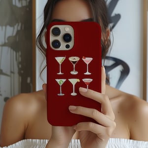 May include: A crimson phone case adorned with watercolour illustrations of cocktails. The case showcases six martini glasses, each containing a different cocktail, with various colours and garnishes. The case is designed for a smartphone.
