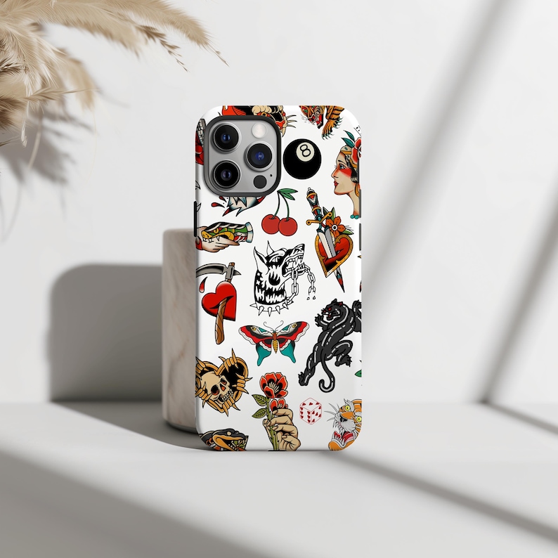May include: White iPhone case with a colorful pattern of traditional tattoo flash designs. The designs include a heart, a dagger, a skull, a butterfly, a panther, a cherry, a tiger, a dice, a snake, a hand holding a flower, and a wolf with a chain.