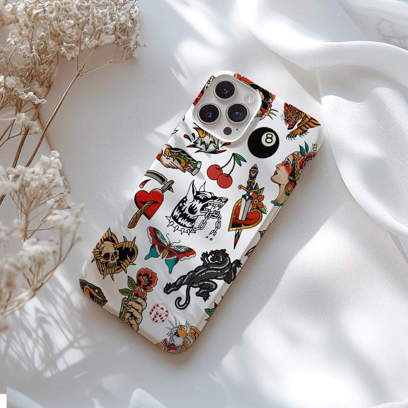 May include: White iPhone case with a colorful tattoo-style design featuring a skull, a heart, a butterfly, a wolf, a panther, a cherry, a dagger, a dice, a woman's face, and a number 8 ball.