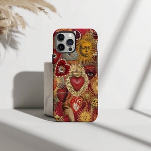 May include: A red, gold and white iPhone case featuring a collage of hearts, suns and eyes. The case has a vintage, ornate design.