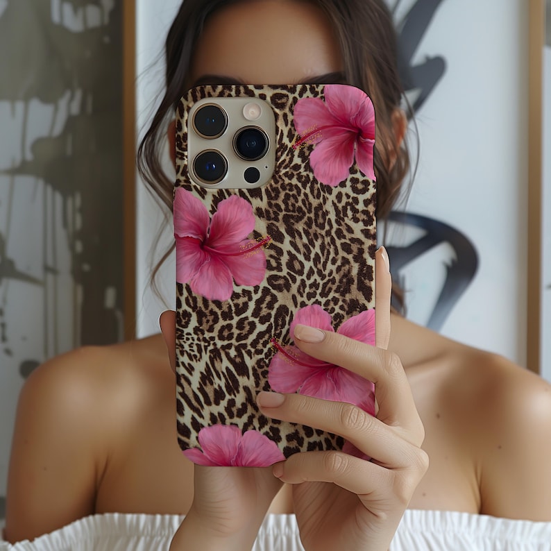 May include: A phone case featuring a leopard print and pink hibiscus flowers. The case is made from a durable material and has a stylish design.