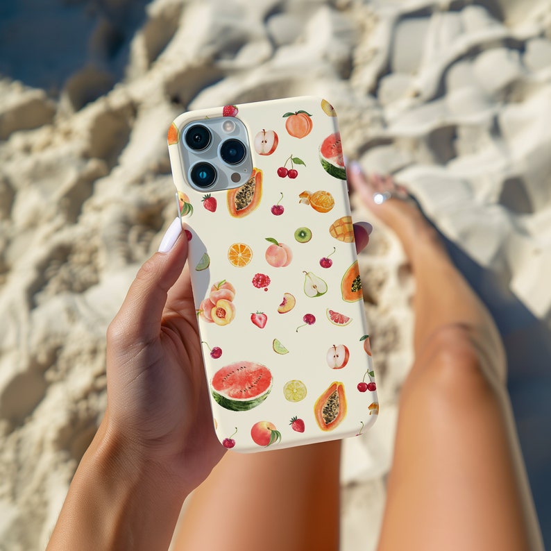 May include: A white phone case with a colorful fruit pattern. The case features a variety of fruits, including watermelon, papaya, peaches, cherries, and limes. The case is designed to fit a smartphone.