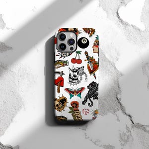 May include: White iPhone case with a colorful pattern of traditional tattoo flash designs. The designs include a skull, a heart, a butterfly, a panther, a cherry, a dagger, a wolf, a snake, a dice, and a number eight.