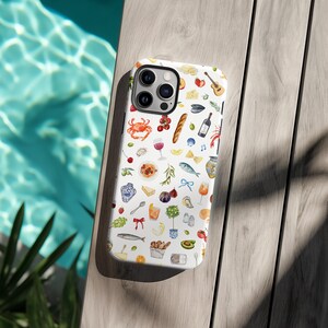 Puede incluir: Funda de tel&eacute;fono blanca con un patr&oacute;n de acuarela de varios alimentos, incluyendo un cangrejo, una copa de vino, una baguette y un pescado. La funda est&aacute; sobre una superficie de madera junto a una piscina.