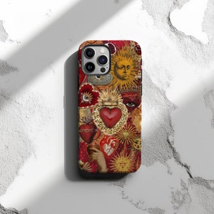 May include: A red, gold and white iPhone case featuring a collage of religious imagery, including a heart, eyes and a sun with a face.