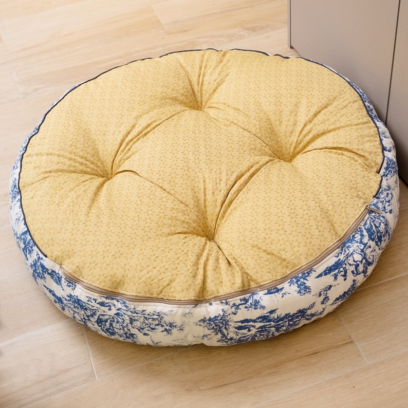 May include: A round, yellow and blue patterned floor cushion with a tufted top.