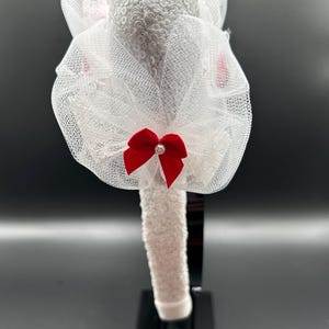 May include: White headband with a white tulle bow and a red satin bow. The headband is decorated with sequins.
