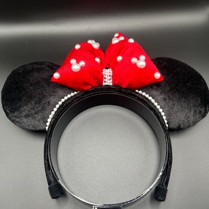 K&ouml;nnte beinhalten: Schwarzer Samt-Minnie-Maus-Ohren-Haarreif mit einer roten Samtschleife und wei&szlig;en Perlenverzierungen.