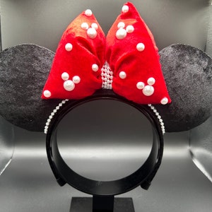K&ouml;nnte beinhalten: Schwarze Samt-Minnie-Maus-Ohren mit einer roten Samtschleife, die mit wei&szlig;en Perlenakzenten verziert ist.