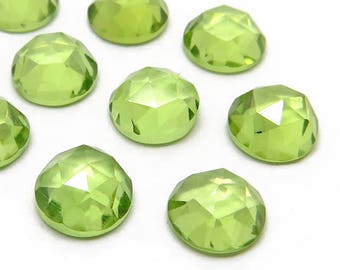 Pode incluir: Dez pedras preciosas de peridoto redondas e facetadas de cor verde. As pedras medem aproximadamente 6 mm de diâmetro e têm um acabamento polido.