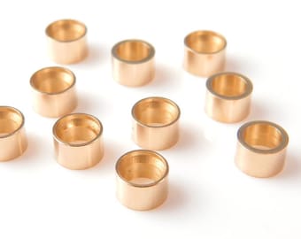 May include: Ten gold-colored metal jump rings, each with a circular opening. The rings are arranged in a scattered pattern on a white surface.