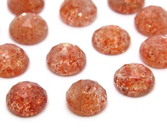 Pode incluir: Uma coleção de 12 cabochões redondos de pedra do sol facetados. As pedras são uma mistura de cores laranja, vermelho e dourado com um acabamento brilhante e iridescente.