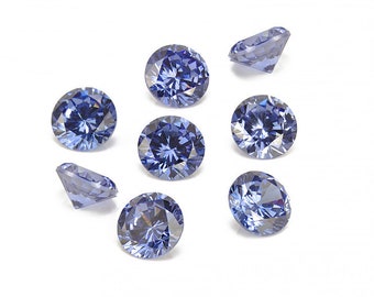 May include: A collection of seven round, faceted, light blue gemstones. The gems are arranged on a white background, with varying angles to showcase their brilliance. The gems are likely for jewelry making or decorative purposes.