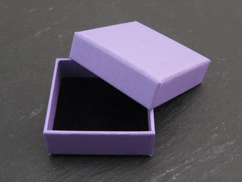 May include: A small, purple gift box with a black velvet interior. The lid is open, revealing the empty interior.