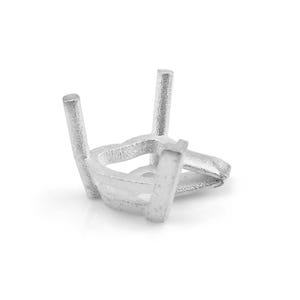 May include: A silver-colored jewelry setting with four prongs and a circular base. The setting is designed to hold a gemstone. The prongs are evenly spaced and rise from the base.