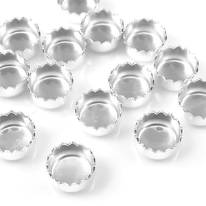 Puede incluir: Un grupo de ajustes de copa de metal de color plateado con bordes festoneados.