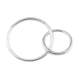 Könnte beinhalten: Zwei ineinandergreifende silberne Ringe, einer größer als der andere, mit einer glatten, polierten Oberfläche.