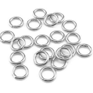 May include: A pile of silver jump rings, a type of jewellery finding used for connecting chains, cords, and other jewellery components.