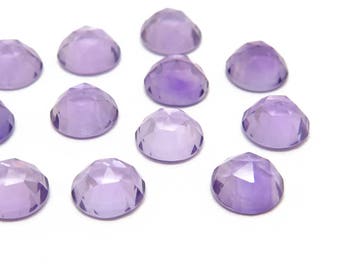 Pode incluir: Uma coleção de doze pedras preciosas redondas de ametista facetadas. As pedras preciosas são de cor púrpura clara e têm um acabamento liso e polido.