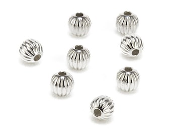 May include: Eight silver round beads with a ridged design. The beads have a hole in the center for stringing.