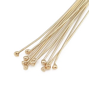 Peut inclure: Un lot d'épingles à tête dorées avec des pointes arrondies. Les épingles sont disposées en éventail.