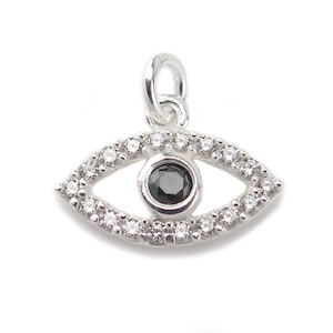 Könnte beinhalten: Ein silberner Anhänger in Form eines bösen Auges mit einem schwarzen Edelstein in der Mitte und einem Rand aus kleinen weißen Edelsteinen.