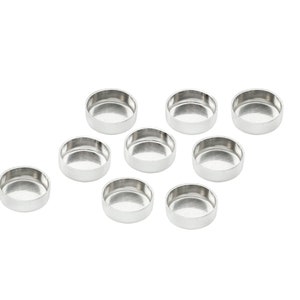 Puede incluir: Diez recipientes redondos de metal de color plateado, posiblemente para joyas u otros objetos pequeños.