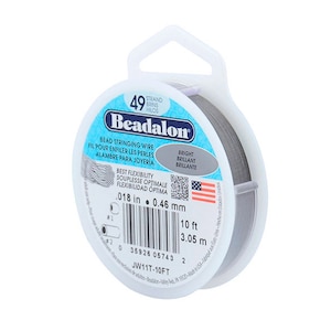 Könnte beinhalten: Eine Spule Beadalon 49-strängiger Perlen-Faden. Der Draht hat einen Durchmesser von 0,46 mm und ist 3,05 Meter lang. Die Spule ist mit dem Beadalon-Logo und dem Text "Best Flexibility" beschriftet.