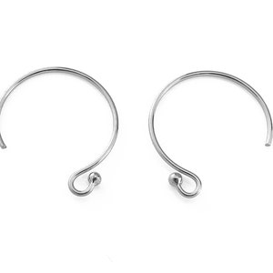 May include: A pair of silver hoop earrings with a small ball at the end of the hook.