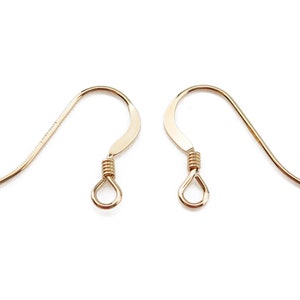 May include: Two gold-coloured earring hooks are shown against a white backdrop. Each hook features a curved design with a looped base and a coiled wire detail. The hooks are designed for jewellery making.