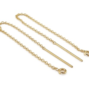 May include: Two gold chains with a small hook at the end of each chain. The chains are hanging from two gold rods.