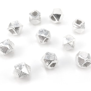 May include: Ten silver-toned metal beads with a geometric, faceted design. Each bead has a hole in the centre for stringing.