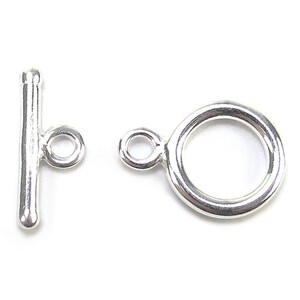 May include: A close-up of a silver toggle clasp, comprising a T-bar and a circular ring with a small loop. This clasp is designed for jewellery making and is set against a white background.
