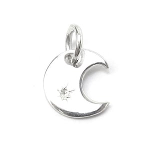 May include: A silver crescent moon charm with a small diamond in the centre.