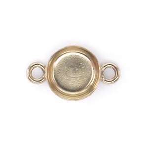 May include: Gold-toned metal connector with a round bezel for a cabochon. The connector has two loops on either side for attaching to jewelry.