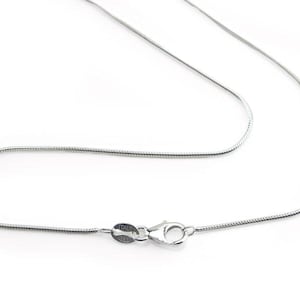 May include: A silver snake chain necklace with a lobster clasp. The necklace is displayed on a white background. The clasp is marked "ITALY" and "925".
