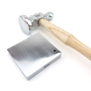 May include: A silver metal hammer with a wooden handle and a square silver metal anvil. The hammer has a round head with a small ball on the end. The anvil has a small hole in the centre.