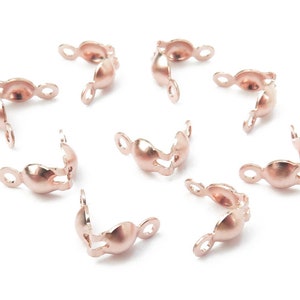Puede incluir: Ocho cierres de metal de color oro rosa para la elaboración de joyas. Cada cierre tiene una forma curva con dos bucles en cada extremo.