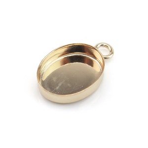 May include: Gold oval pendant setting with a loop for attaching a chain or cord. The setting is designed to hold a cabochon stone.