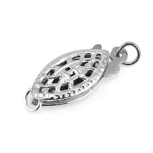 Könnte beinhalten: Ein silberfarbener Schmuckverschluss im Filigranstil. Der Verschluss hat die Form eines Blattes mit einem aufwendigen, durchbrochenen Design. Er hat an jedem Ende eine kleine Schlaufe zum Befestigen an Schmuck und einen sicheren Verschlussmechanismus.