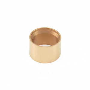 Puede incluir: Un anillo de metal de color dorado con una superficie lisa y redondeada. El anillo tiene un diámetro de aproximadamente 2,5 cm y un borde ligeramente elevado.