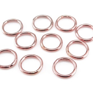 May include: Ten rose gold jump rings, each with a smooth, rounded finish. These rings are ideal for jewellery making and crafting.